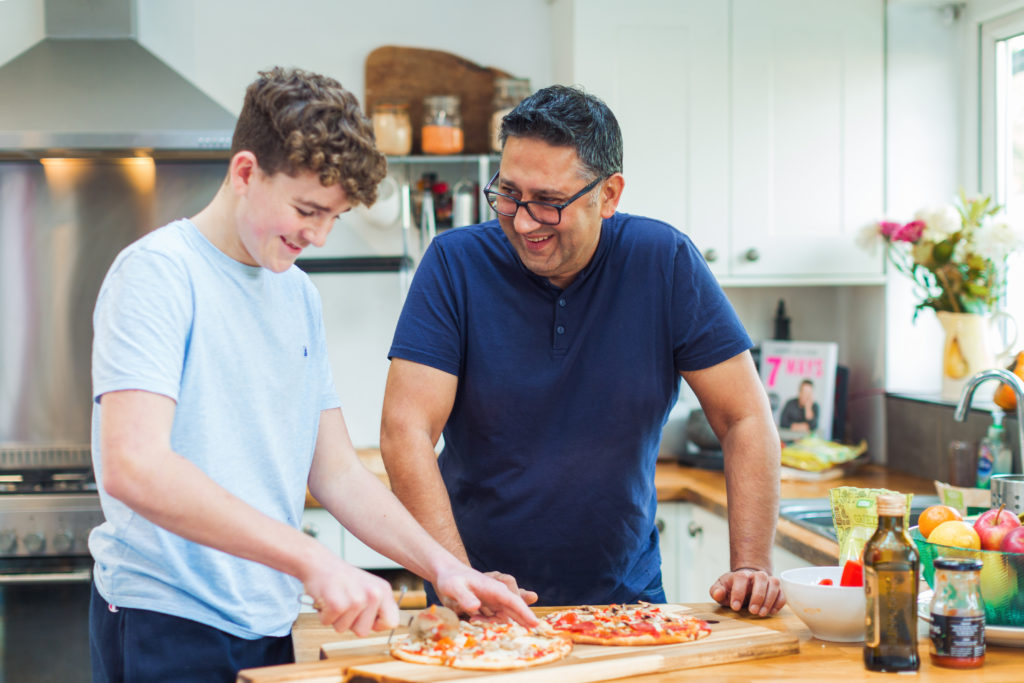Adult with teenage boy in kitchen making food together