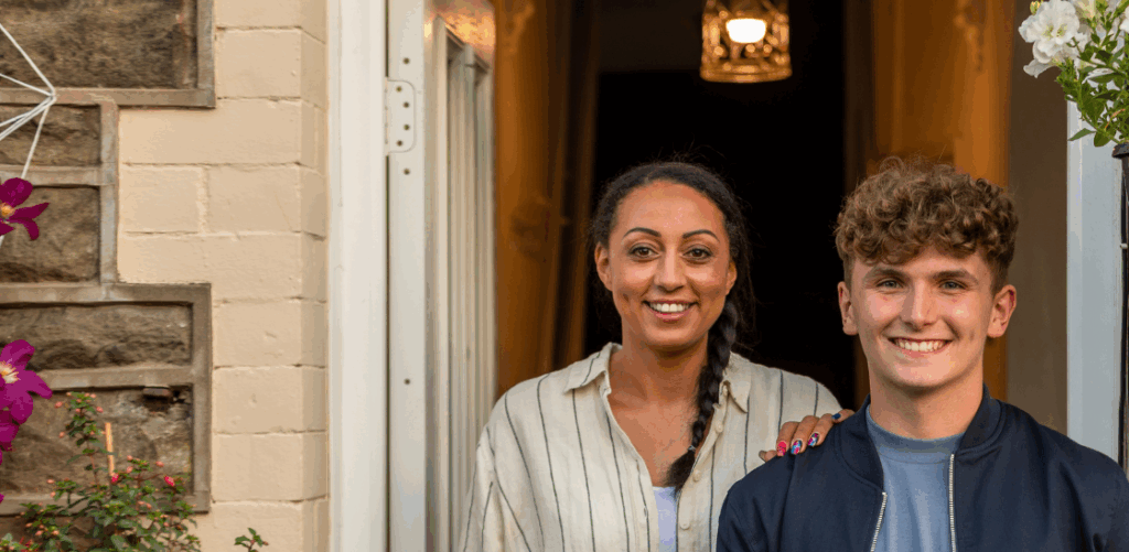 Male and female smiling for a photo in front of house